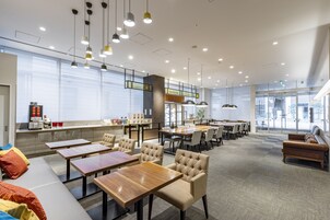 Un moderno vestíbulo de hotel con una zona de estar, mesas y una estación de café.