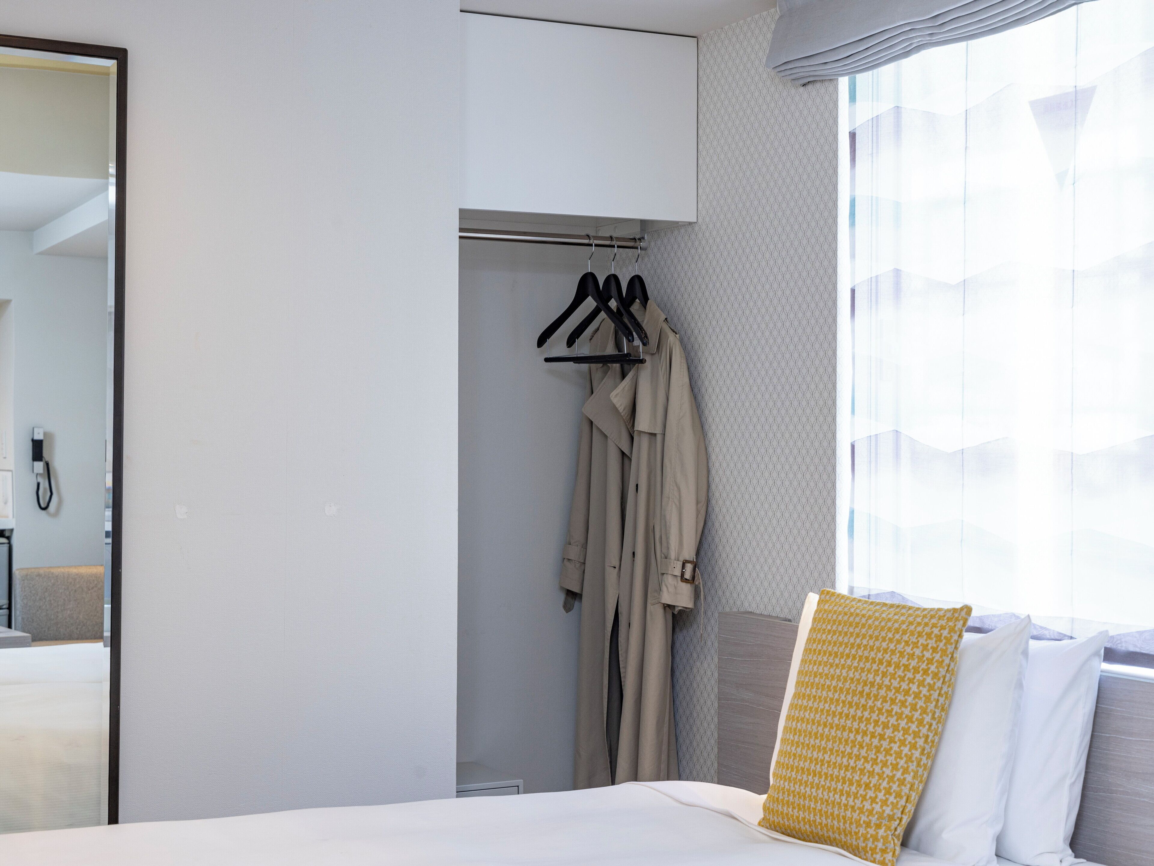 A hotel room with a bed, a wardrobe, and a mirror.