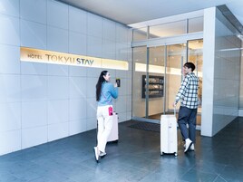 A modern hotel entrance with a sign reading "HOTEL TOKYU STAY".