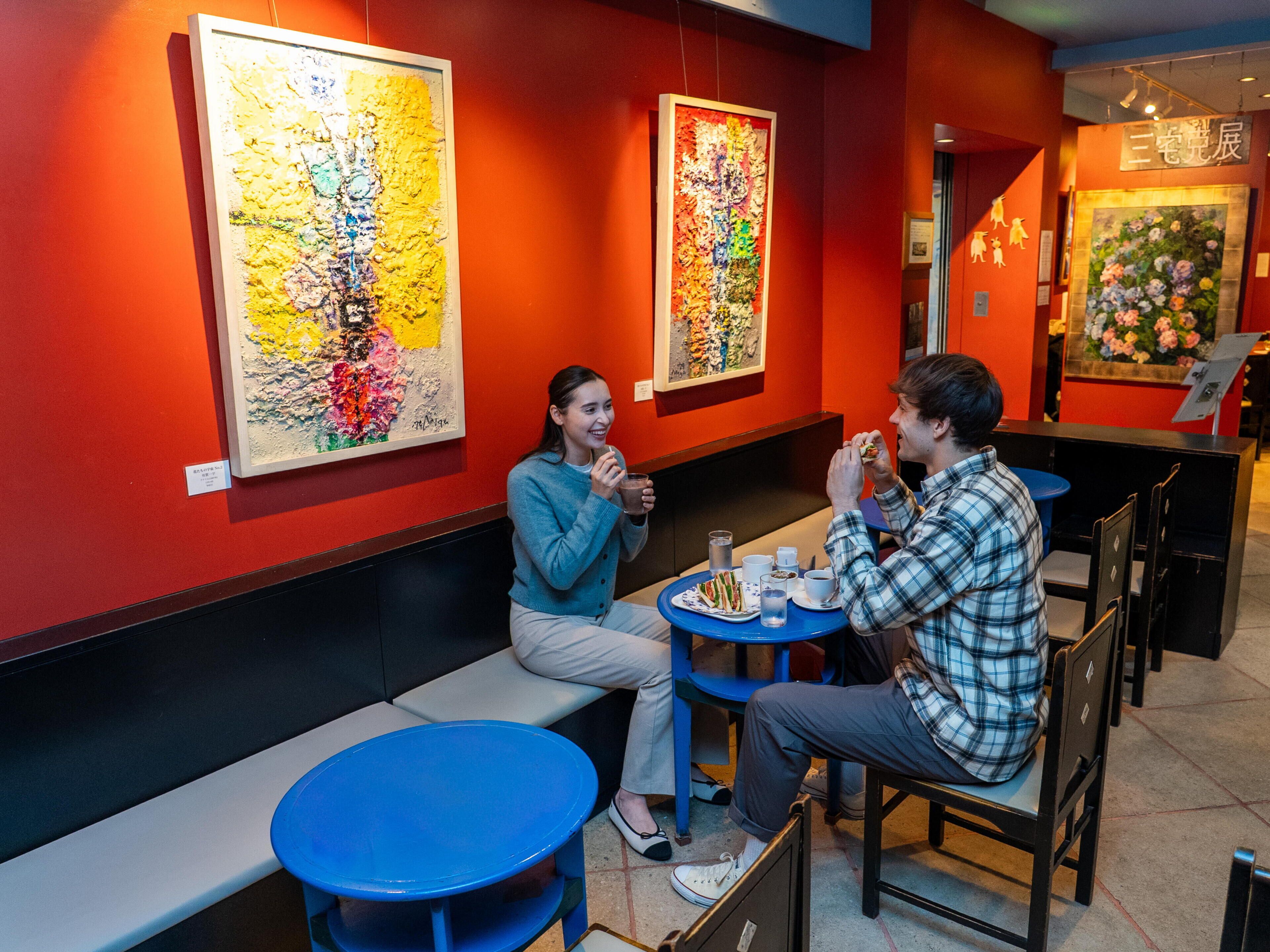 A restaurant with red walls, blue tables, and artwork on the walls.