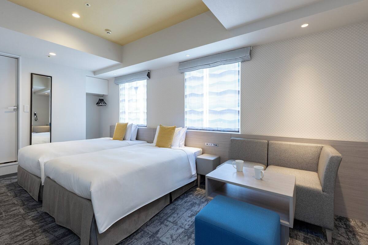 A modern hotel room with a large bed, a seating area, and a small table.