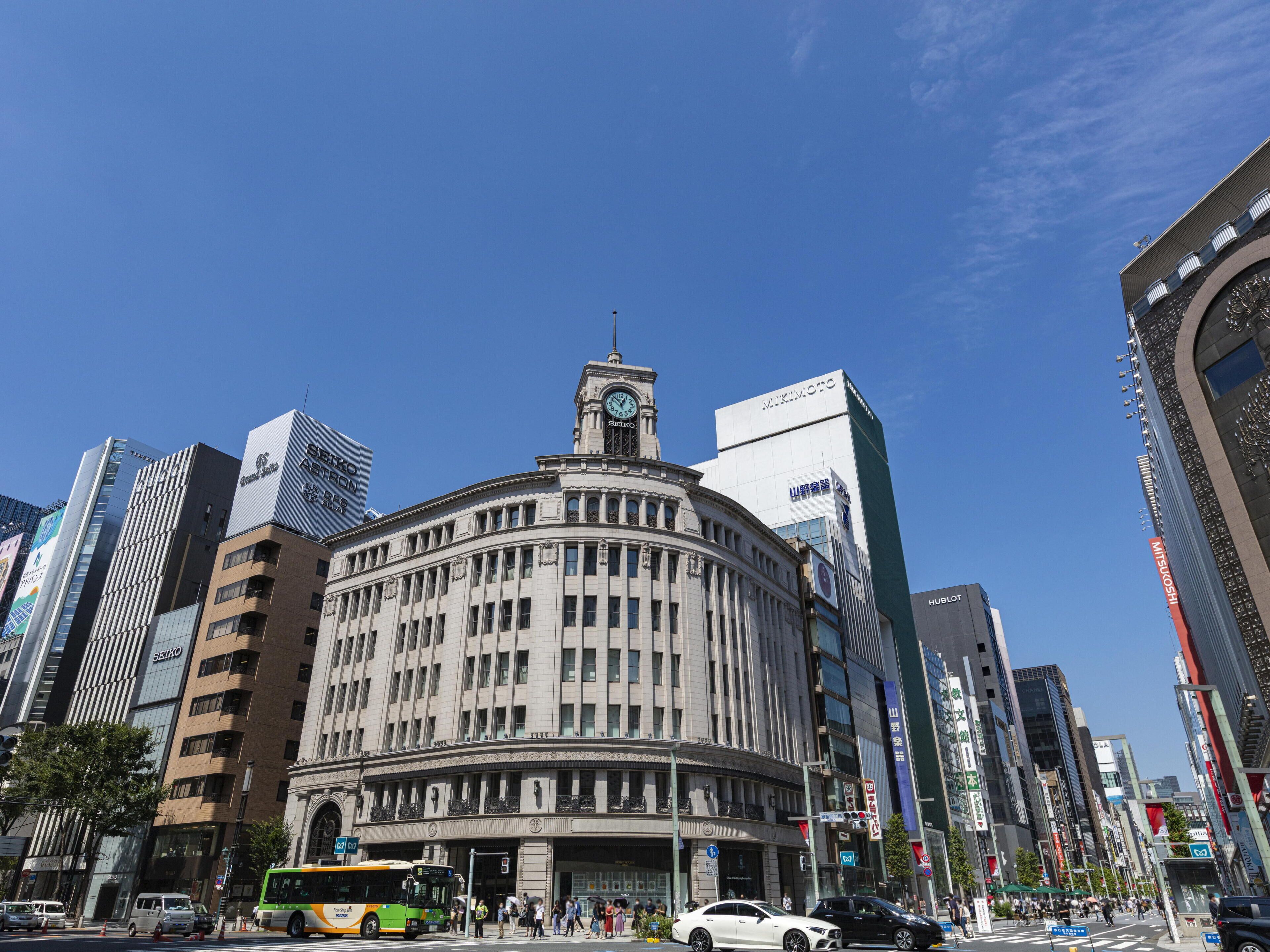 A historic building with a clock tower, surrounded by modern skyscrapers.