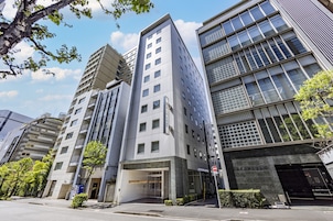 Un edificio moderno con fachada de vidrio, varios pisos y una entrada destacada.