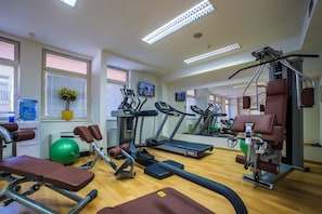 Un gimnasio con cintas de correr, bicicletas estáticas y máquinas de pesas.