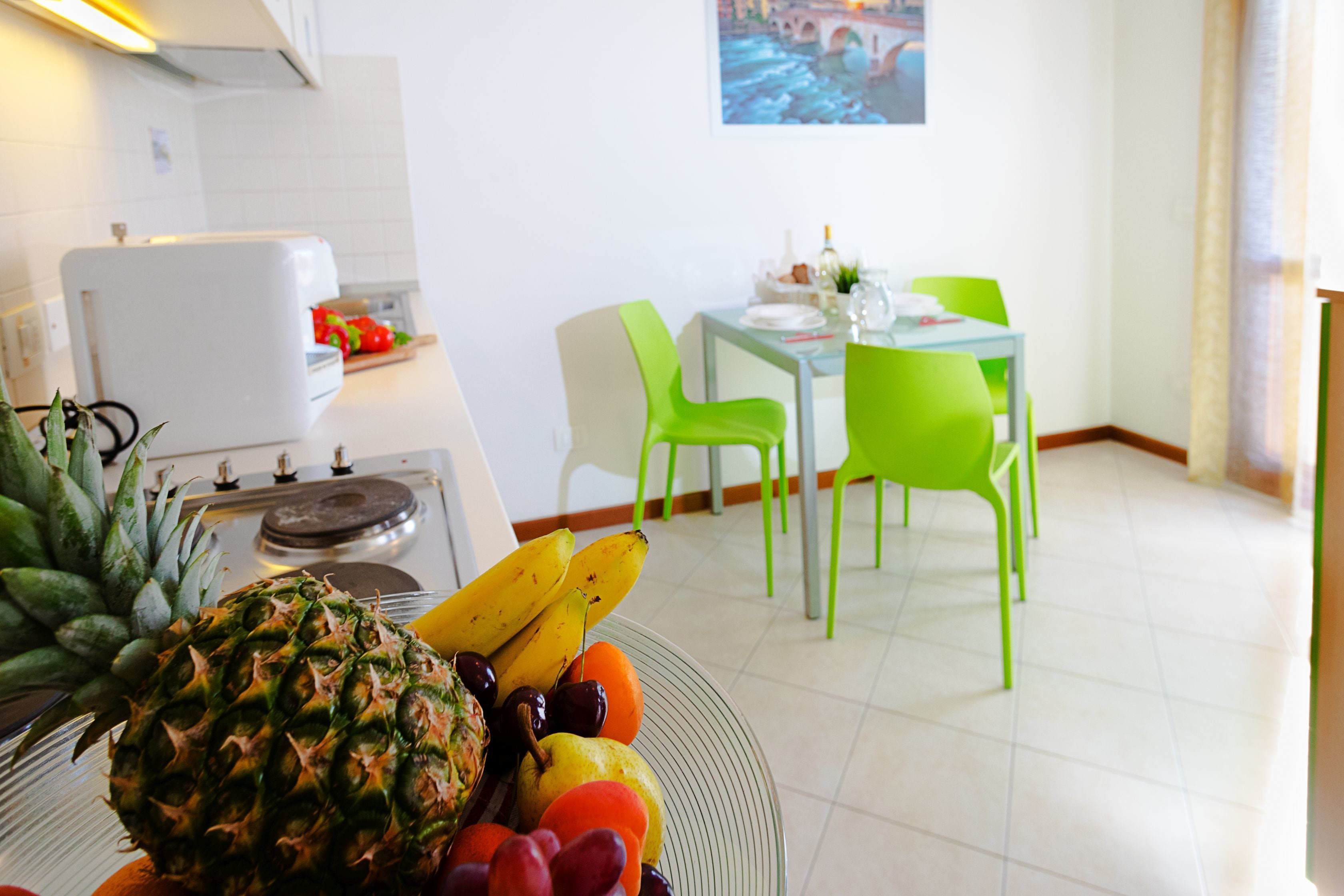 A kitchen with a dining area, featuring a table with chairs and a fruit bowl on the counter.
