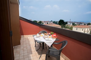 Enjoy breakfast on the balcony with a table set for two, featuring a teapot, bread, and a refreshing glass of juice.