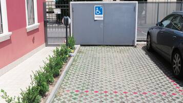 Ein Parkplatz mit Parkplatz für Behinderte-Kennzeichnung, einem Auto und einem Gebäude mit roter Wand und Tor.