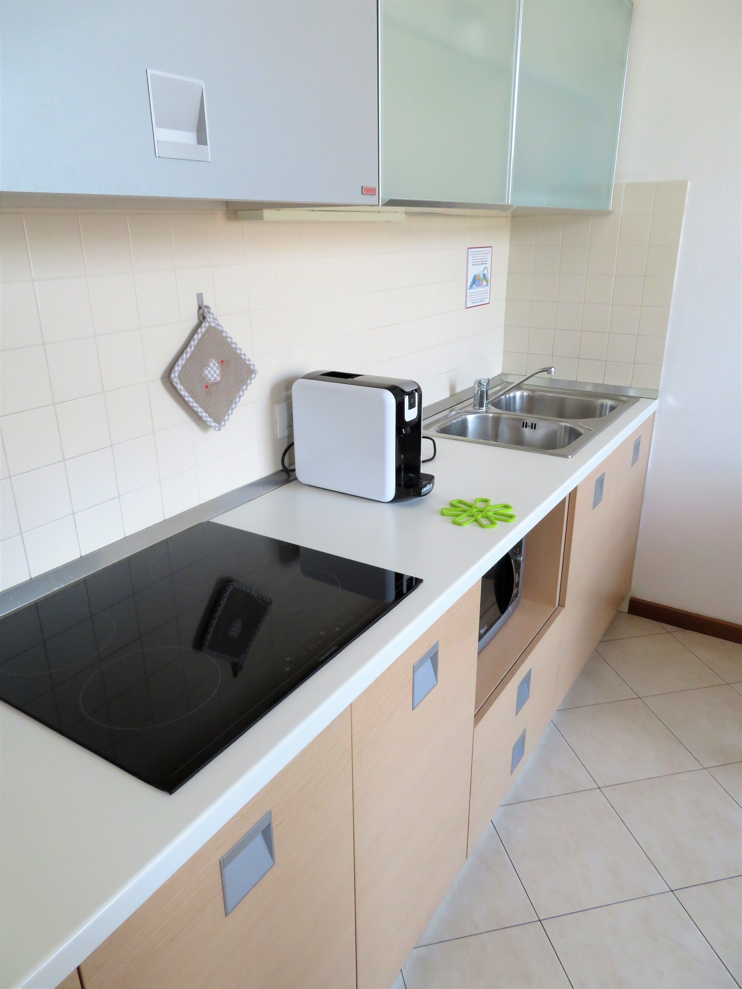 A modern kitchen with a black induction cooktop, a built-in toaster, and a stainless steel sink.