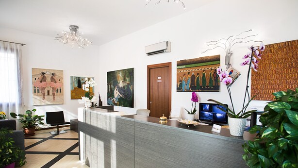Un área de recepción con un mostrador moderno, plantas en macetas, obras de arte en las paredes y un televisor.