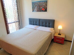 Relax in a cozy retreat with a neatly made bed, tufted headboard, and soft lighting from the bedside lamp.