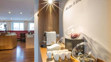 A hotel reception area with a wooden counter, a coffee machine, and a wall with a sign.