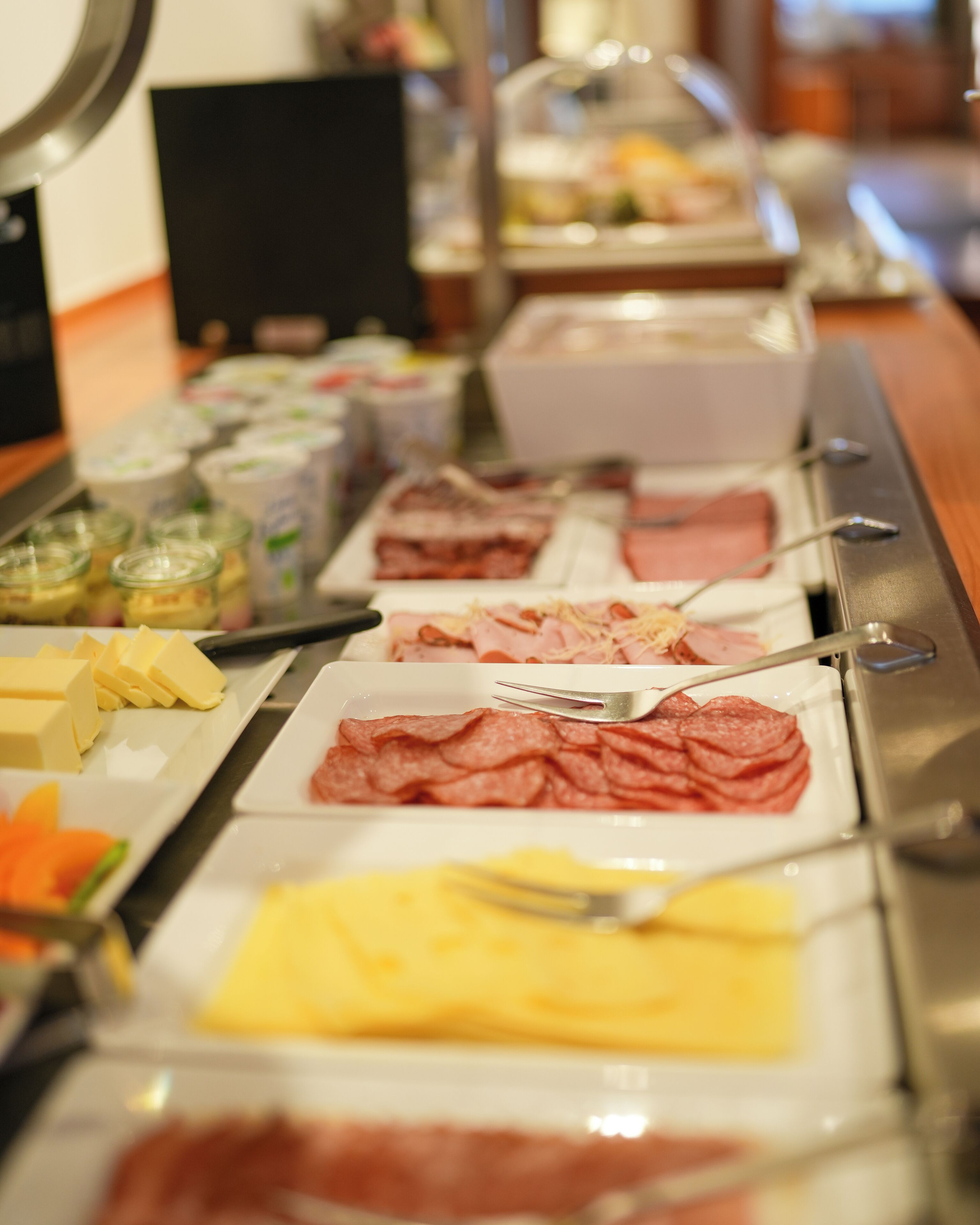 Un buffet con diverse pietanze, tra cui carni, formaggi e verdure.