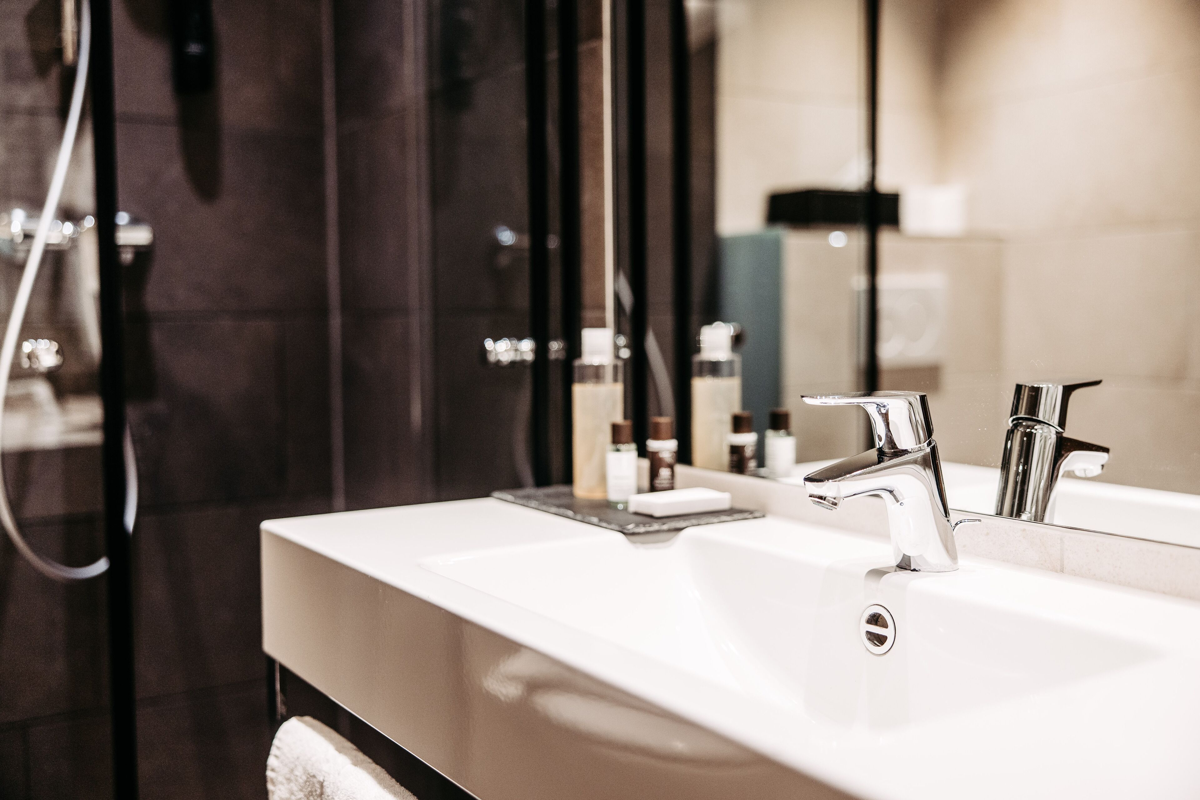 Un bany modern amb un mirall gran, un lavabo blanc i una zona de dutxa.