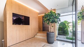Un interior moderno con una pared de madera, una planta grande en maceta y vistas al exterior a través de un ventanal.