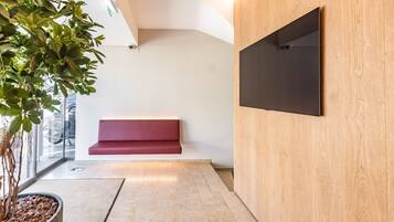 A modern reception area with a wooden wall, a red bench, and a potted plant.