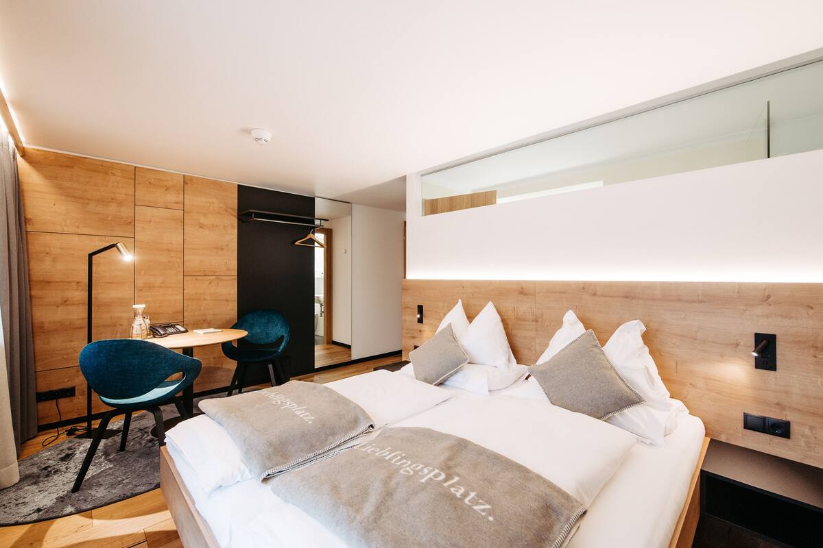 A modern hotel room with a bed, a desk, and a chair.