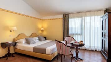 Une chambre d’hôtel comprenant un lit, des tables de chevet, une chaise, une petite table avec une tasse et une assiette, et une armoire.