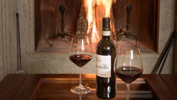 Lareira com uma garrafa de vinho e duas taças sobre uma mesa de madeira.