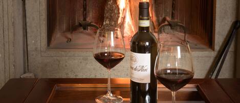 Una chimenea con una botella de vino y dos copas sobre una mesa de madera.