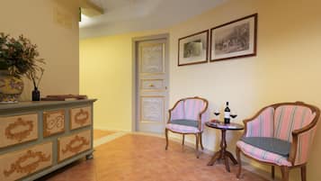 Un pasillo con un banco de madera, una pequeña mesa con una botella y vasos, y una puerta con un panel decorativo.