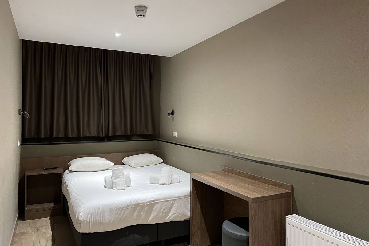 Ein modernes Hotelzimmer mit Bett, Nachttisch und Schreibtisch.