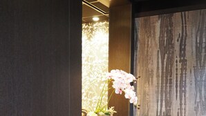 A modern dining area with a dark wooden table and chairs, a decorative flower arrangement, and a textured wall.
