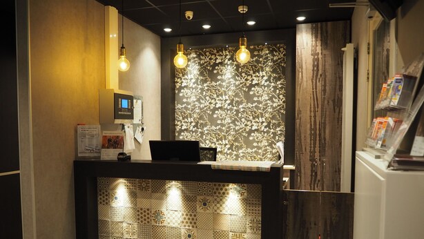 A reception desk with a digital screen, a bike rental sign, and a patterned wall.