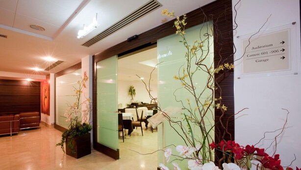 A hotel lobby with a reception desk, seating area, and directional signs for the auditorium, camera rooms, and garage. - Centrum Palace (Campobasso)