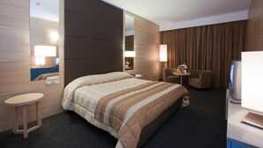 A hotel room with a large bed, two bedside tables, a desk, a chair, a TV, and a mirror. - Centrum Palace (Campobasso)