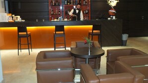 A bar area with leather seating, a bartender, and a well-stocked liquor shelf. - Centrum Palace (Campobasso)