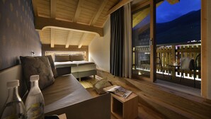 A cozy room with a bed, a small table, and a window overlooking a wooden deck. - Hotel Galli's - Centro (Livigno)