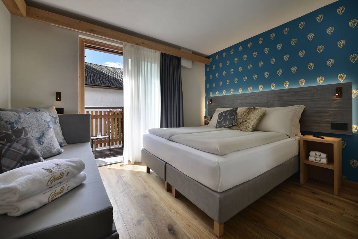 A bedroom with a bed, a sofa, and a wooden nightstand.