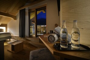 A wooden table with two bottles of Acqua di Livigno water, a rolled towel, and a black object on a tray. - Hotel Galli's - Centro (Livigno)
