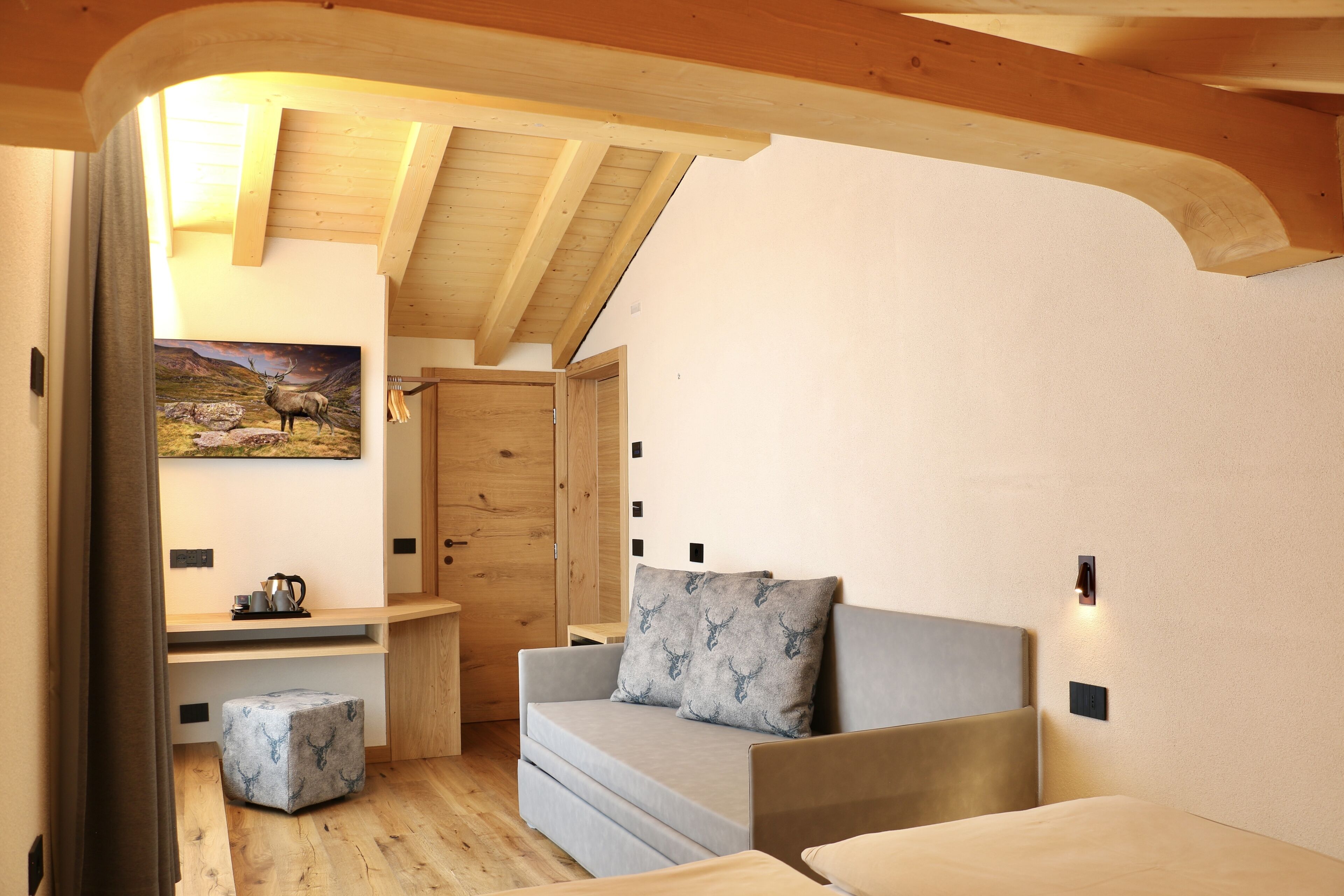 A cozy room with a sofa, ottoman, and a painting of a deer.