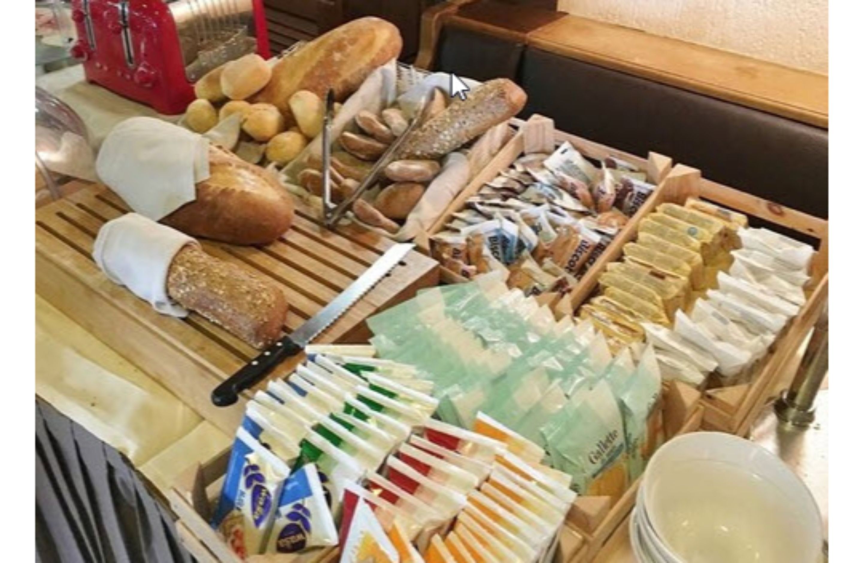 A buffet table with various breads, pastries, and packaged food items.