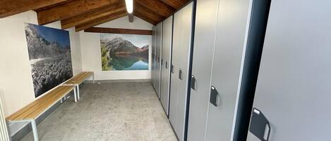 A room with a wooden ceiling, a bench, lockers, and two large landscape paintings.