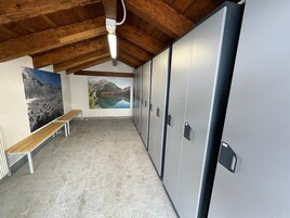 Quarto com teto de madeira, um banco, armários e duas grandes pinturas de paisagens.