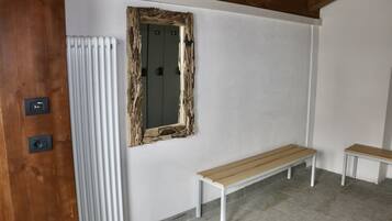 Une pièce avec un banc en bois, un radiateur et un miroir doté d’un cadre rustique.