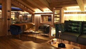 A cozy interior with wooden beams, a bar area, and a seating area with a sofa and chairs. - Hotel Galli's - Centro (Livigno)