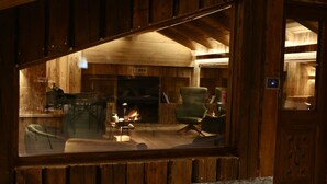 A cozy room with a fireplace, wooden walls, and a comfortable seating area. - Hotel Galli's - Centro (Livigno)
