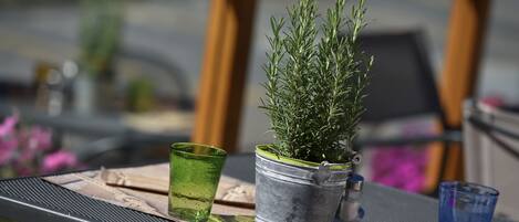 Una mesa de metal con una planta en maceta, dos vasos y un posavasos de madera.