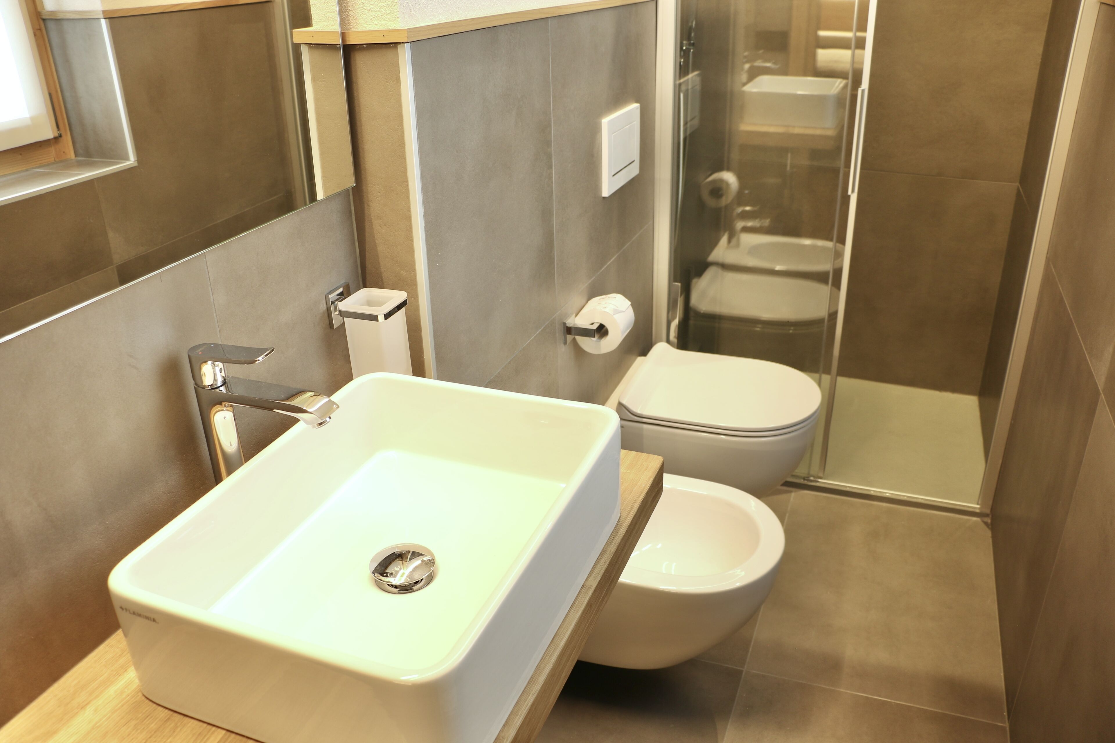 A modern bathroom with a white sink, toilet, and glass shower enclosure.