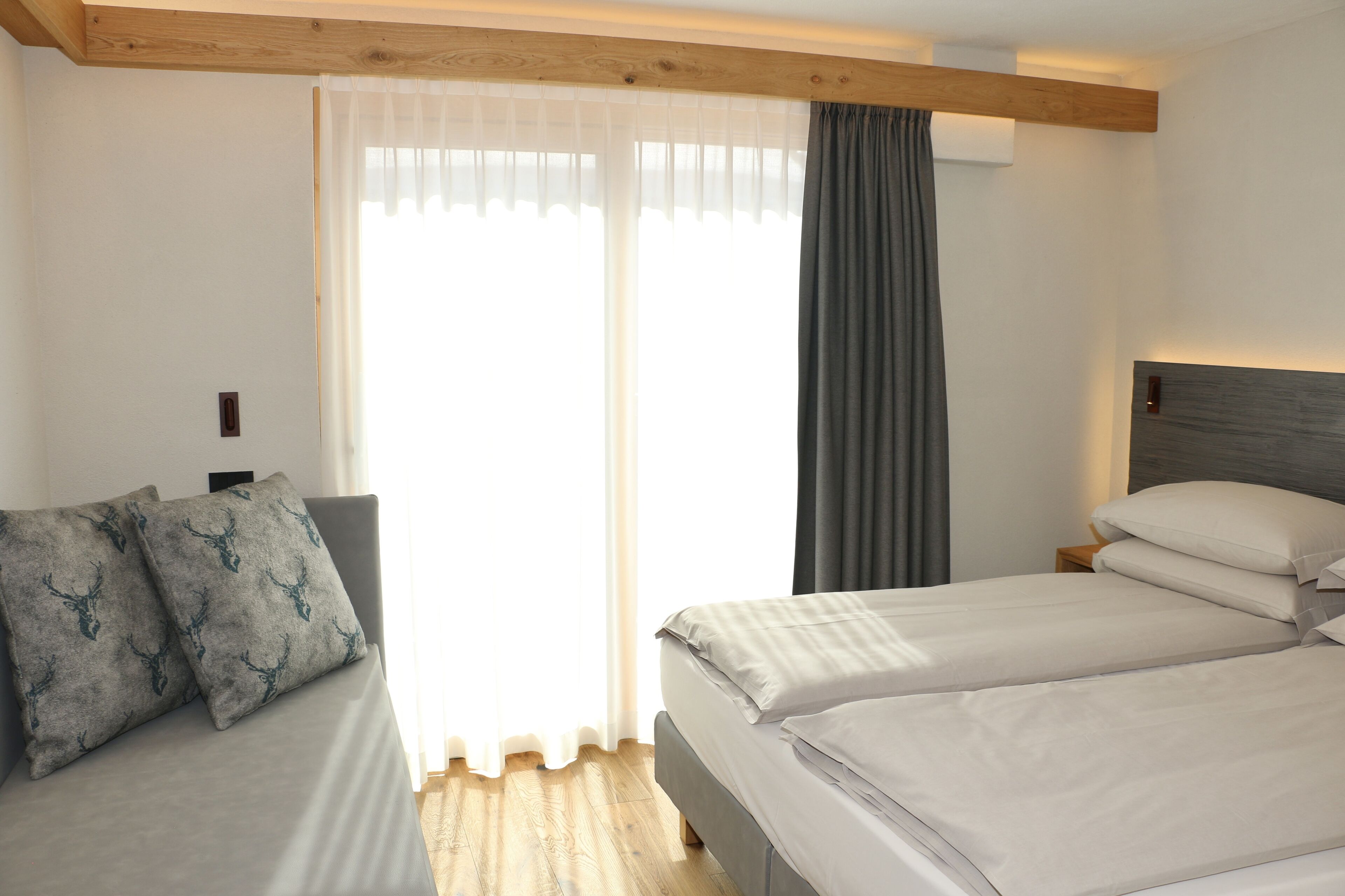 A hotel room with a bed, a sofa, and a window with curtains.