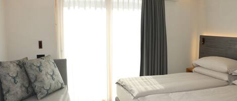 A hotel room with a bed, a sofa, and a window with curtains.