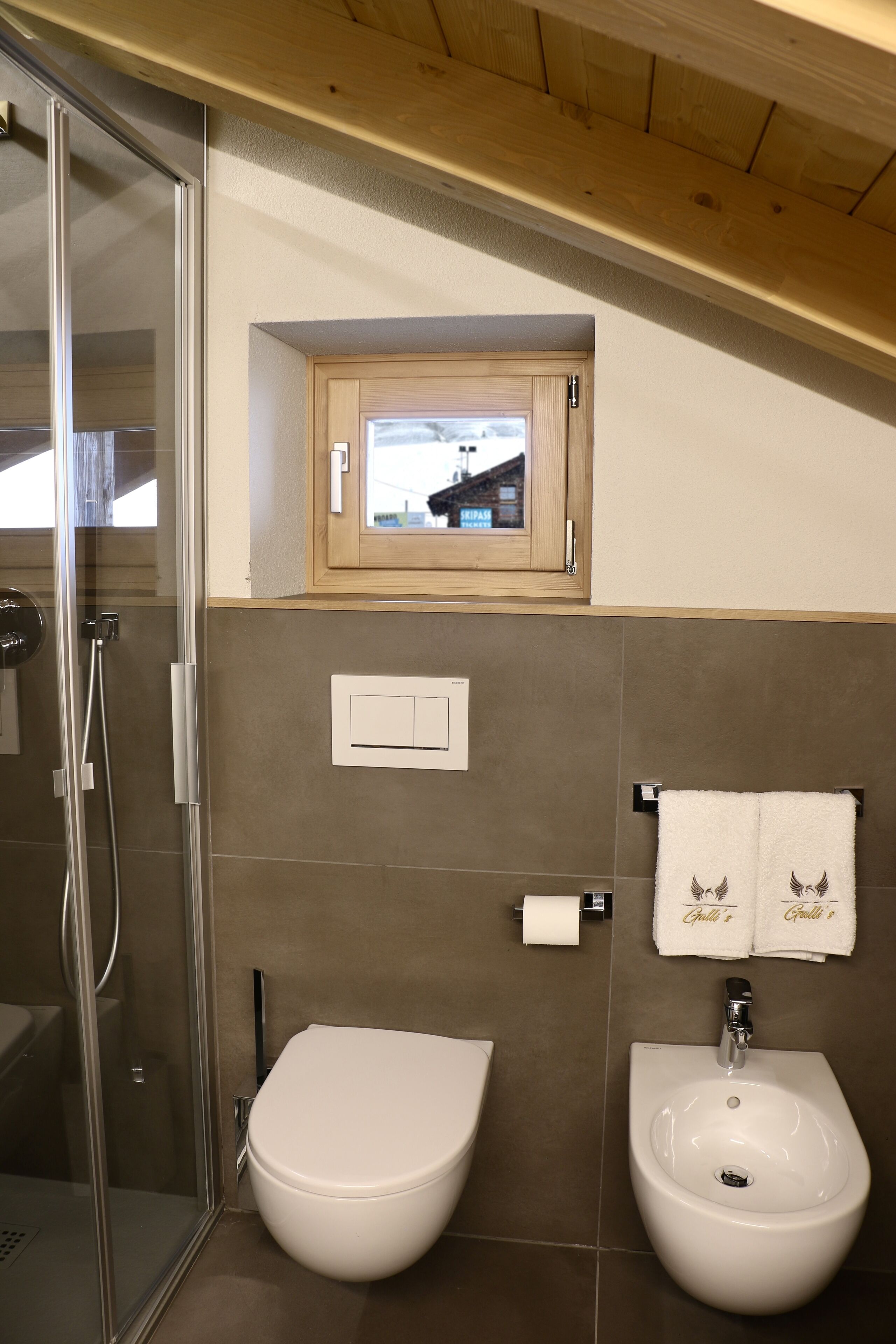 A bathroom with a glass shower enclosure, a toilet, and a bidet.