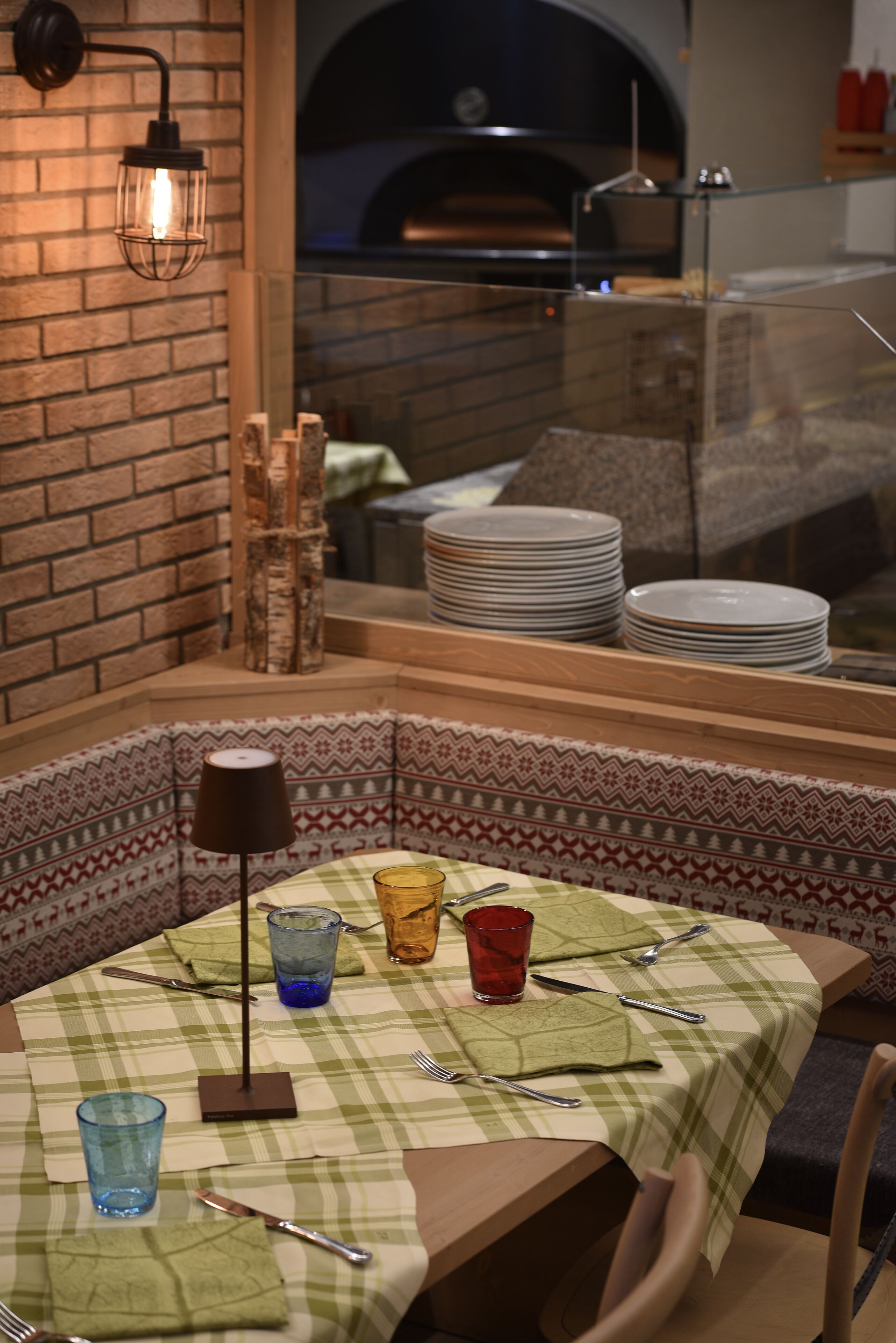 A cozy corner with a table set for dining, a brick wall, and a view of a brick oven.