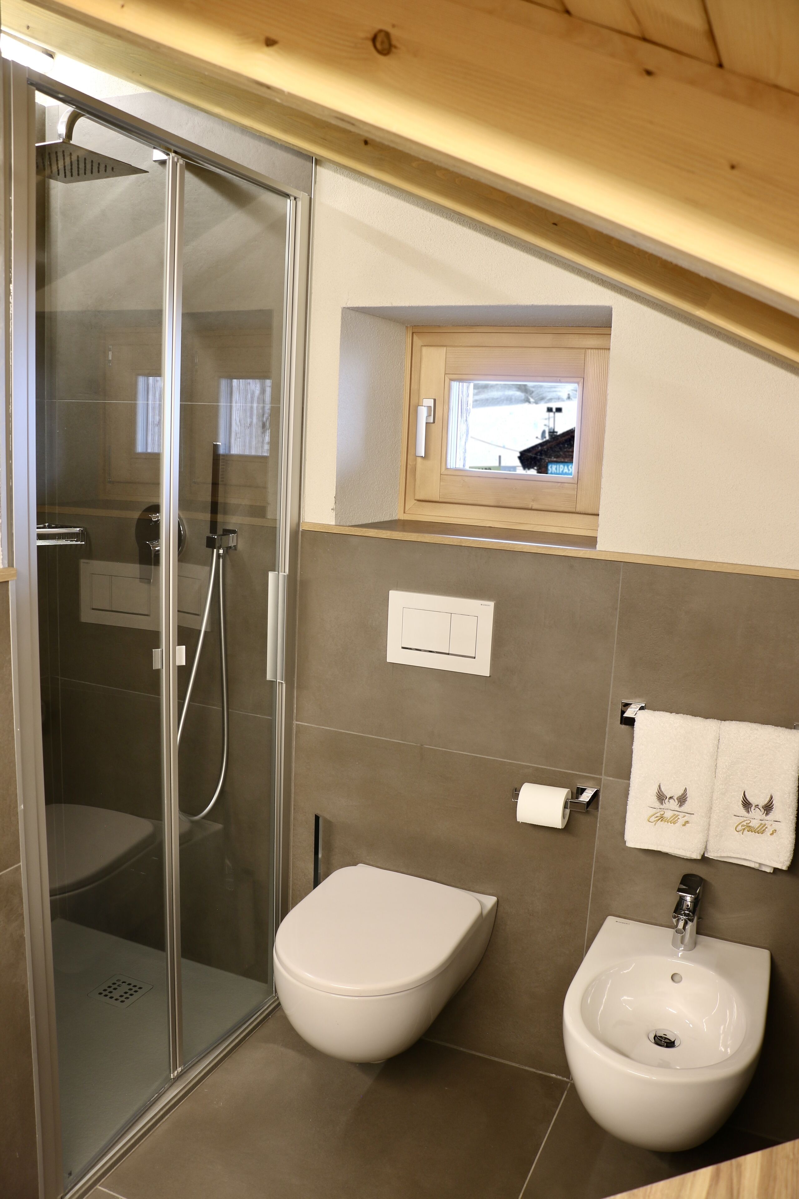 Un baño con ducha envuelta en vidrio, inodoro y lavamanos con espejo.