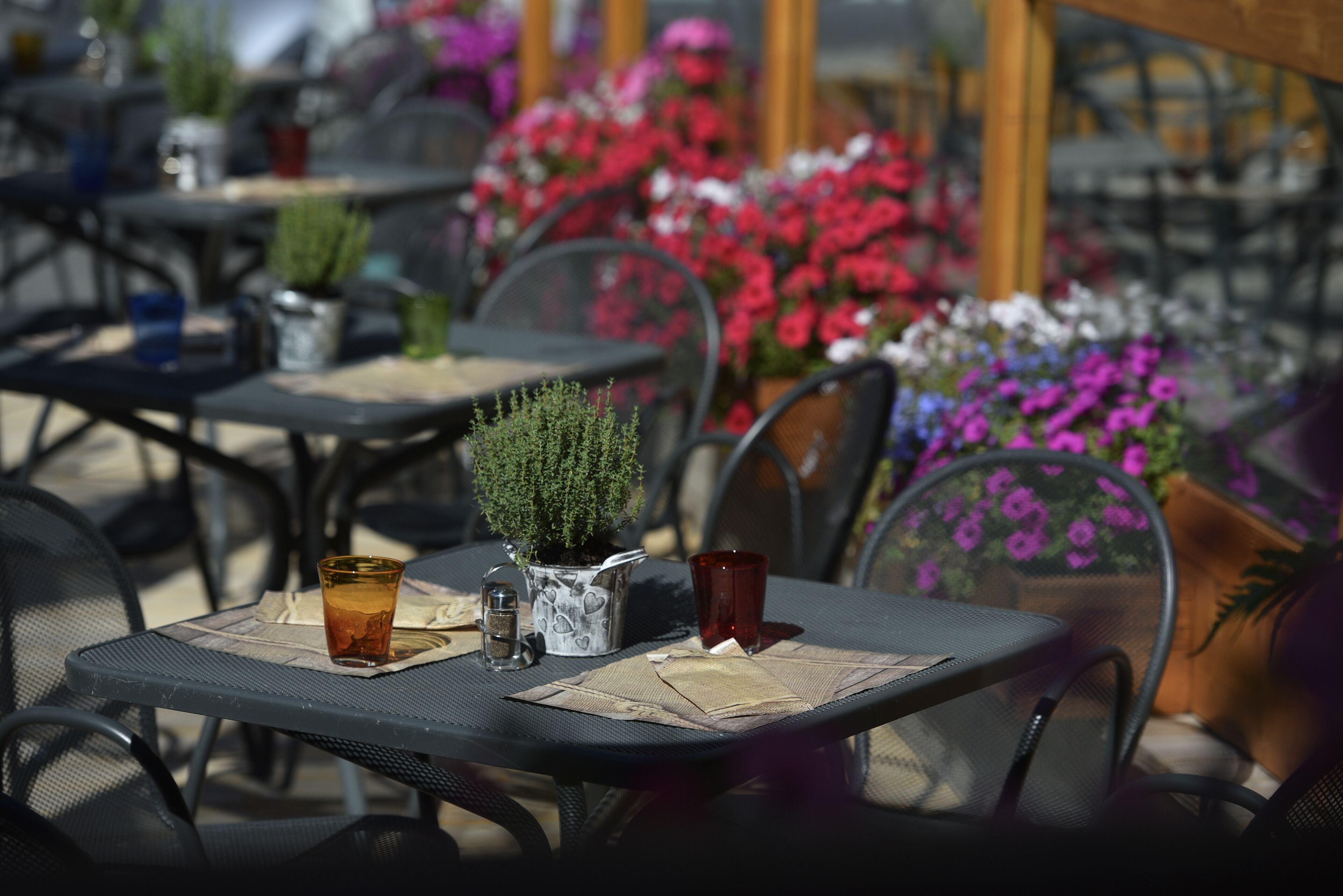An outdoor cafe with tables, chairs, and potted plants.