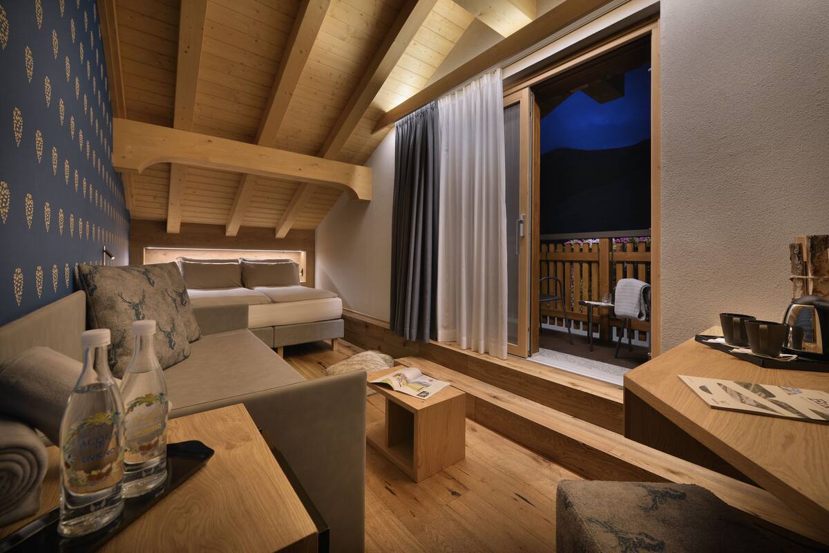 A cozy room with a wooden ceiling, a sofa, a small table with a book, and a window with curtains.