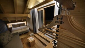 A cozy wooden interior with a sofa, a small table, and a staircase leading to a balcony. - Hotel Galli's - Centro (Livigno)